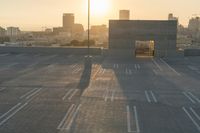 an empty parking lot overlooking the city skyline at sunset time with an airplane taking off