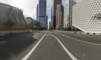 an empty city street in the middle of a big cityscape with tall buildings