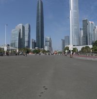 a city skyline with many tall buildings and people walking on a walkway along it, with a person in a stroller and one man walking away