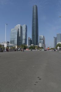 a city skyline with many tall buildings and people walking on a walkway along it, with a person in a stroller and one man walking away