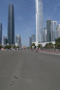 a city skyline with many tall buildings and people walking on a walkway along it, with a person in a stroller and one man walking away