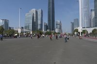 a city skyline with many tall buildings and people walking on a walkway along it, with a person in a stroller and one man walking away