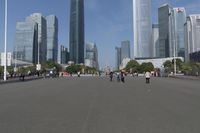 a city skyline with many tall buildings and people walking on a walkway along it, with a person in a stroller and one man walking away