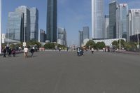 a city skyline with many tall buildings and people walking on a walkway along it, with a person in a stroller and one man walking away