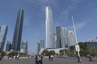 a city skyline with many tall buildings and people walking on a walkway along it, with a person in a stroller and one man walking away