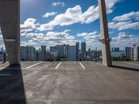 a city skyline from an empty roof with a bright blue sky and clouds overhead, with an empty parking lot