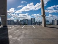 a city skyline from an empty roof with a bright blue sky and clouds overhead, with an empty parking lot