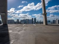 a city skyline from an empty roof with a bright blue sky and clouds overhead, with an empty parking lot