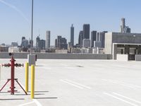 a yellow fire hydrant sitting in a parking lot next to a city skyline with tall buildings