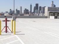 a yellow fire hydrant sitting in a parking lot next to a city skyline with tall buildings