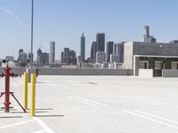 a yellow fire hydrant sitting in a parking lot next to a city skyline with tall buildings