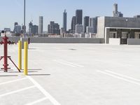 a yellow fire hydrant sitting in a parking lot next to a city skyline with tall buildings