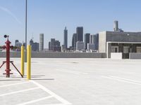 a yellow fire hydrant sitting in a parking lot next to a city skyline with tall buildings