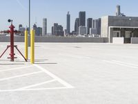 a yellow fire hydrant sitting in a parking lot next to a city skyline with tall buildings