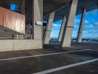 an empty parking lot has concrete pillars and walls that connect with each other in the background