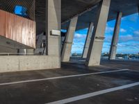 an empty parking lot has concrete pillars and walls that connect with each other in the background