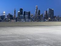 an empty parking lot with city skyline in background at dusk time in this city of lights