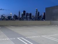 an empty parking lot with city skyline in background at dusk time in this city of lights