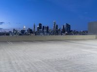 an empty parking lot with city skyline in background at dusk time in this city of lights