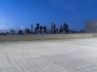 an empty parking lot with city skyline in background at dusk time in this city of lights