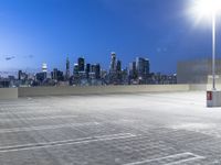 an empty parking lot with city skyline in background at dusk time in this city of lights