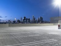 an empty parking lot with city skyline in background at dusk time in this city of lights