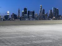 an empty parking lot with city skyline in background at dusk time in this city of lights