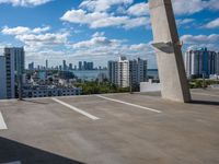 view from atop of a building with a parking area near by on the ground and large skyscrapers with high rise buildings in the distance