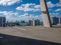 view from atop of a building with a parking area near by on the ground and large skyscrapers with high rise buildings in the distance