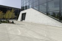 a person riding a skateboard on a cement patio near a building, near a park