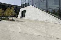 a person riding a skateboard on a cement patio near a building, near a park