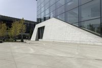 a person riding a skateboard on a cement patio near a building, near a park