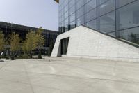 a person riding a skateboard on a cement patio near a building, near a park