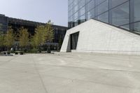 a person riding a skateboard on a cement patio near a building, near a park