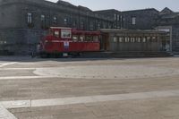 a trolley is sitting alone on the ground in the city square near many large buildings