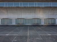 two empty parking spaces with two empty doors and a large window on the wall between two buildings