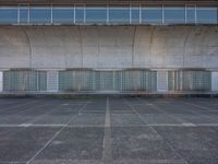 two empty parking spaces with two empty doors and a large window on the wall between two buildings