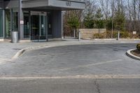 a building has a glass front door, and a small fire hydrant on the curb