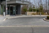 a building has a glass front door, and a small fire hydrant on the curb