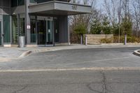 a building has a glass front door, and a small fire hydrant on the curb