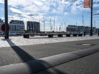 a city street with several benches sitting in the middle of it and boats anchored at the dock