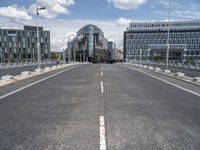 the empty city street is pictured during the day time, near buildings and benches,