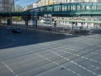 cars and buses on the street and in front of a pedestrian walkway near a green pedestrian bridge