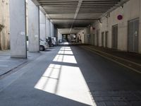 sunlight shining on parking garage's and parking meters in city street with cars parked underneath structure