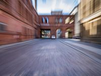 a blurry photograph of a city street and buildings in motion as it runs by