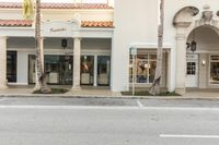 a man rides a bike down the road on a city street past a building with pillars