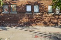 a fire hydrant on the side of a sidewalk near a brick building with windows