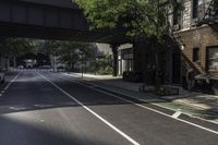 a bus drives down the street under an overpass in this city alley and sidewalk