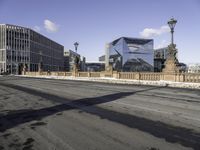 a city street with buildings and a bridge in the middle of it and the shadow of a man walking across a paved street from it