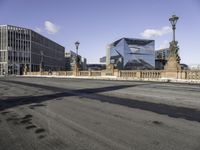 a city street with buildings and a bridge in the middle of it and the shadow of a man walking across a paved street from it